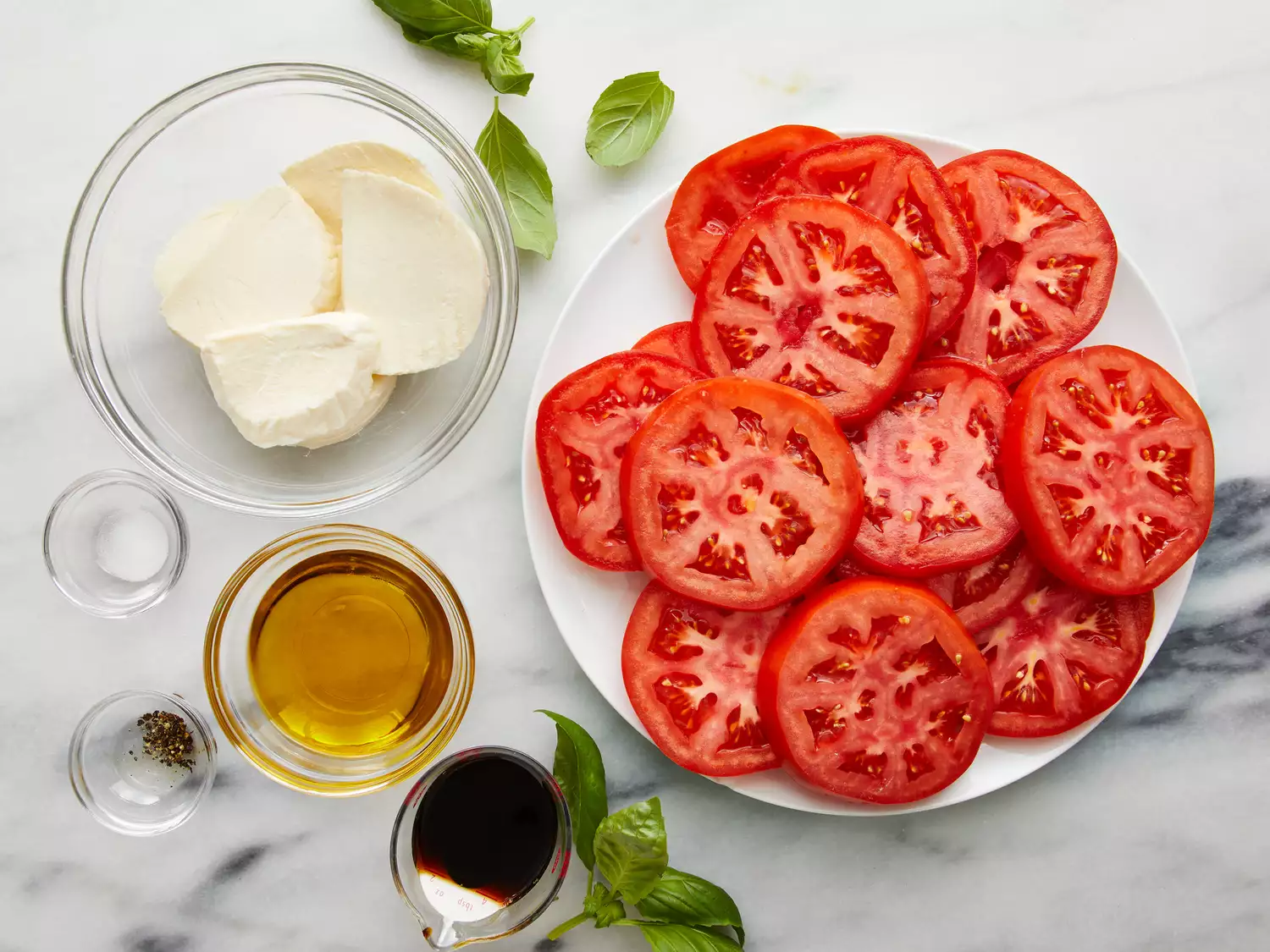 Sliced tomatoes and mozzarella arranged in an alternating pattern on a white platter